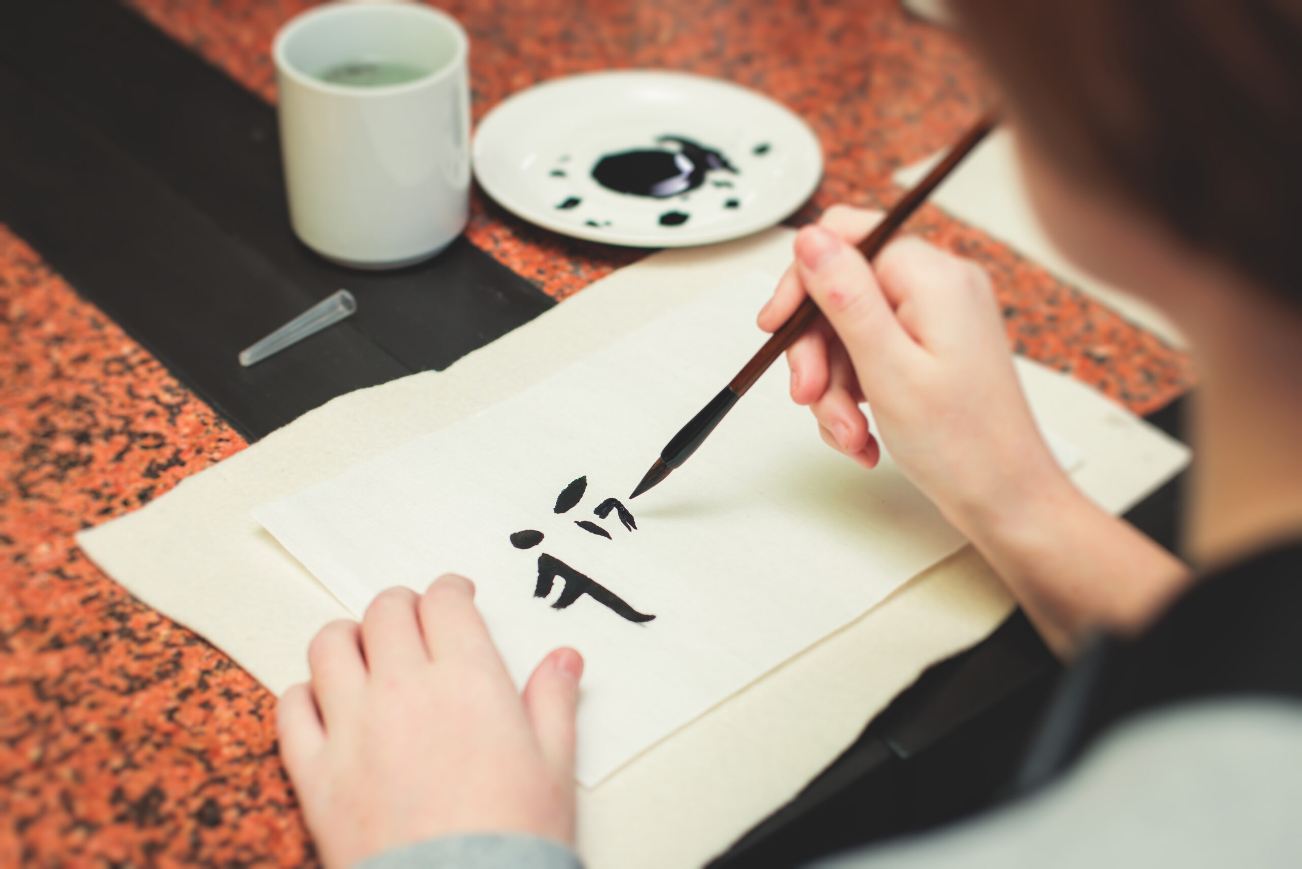 Nainen kirjoittaa kiinalaisia merkkejä